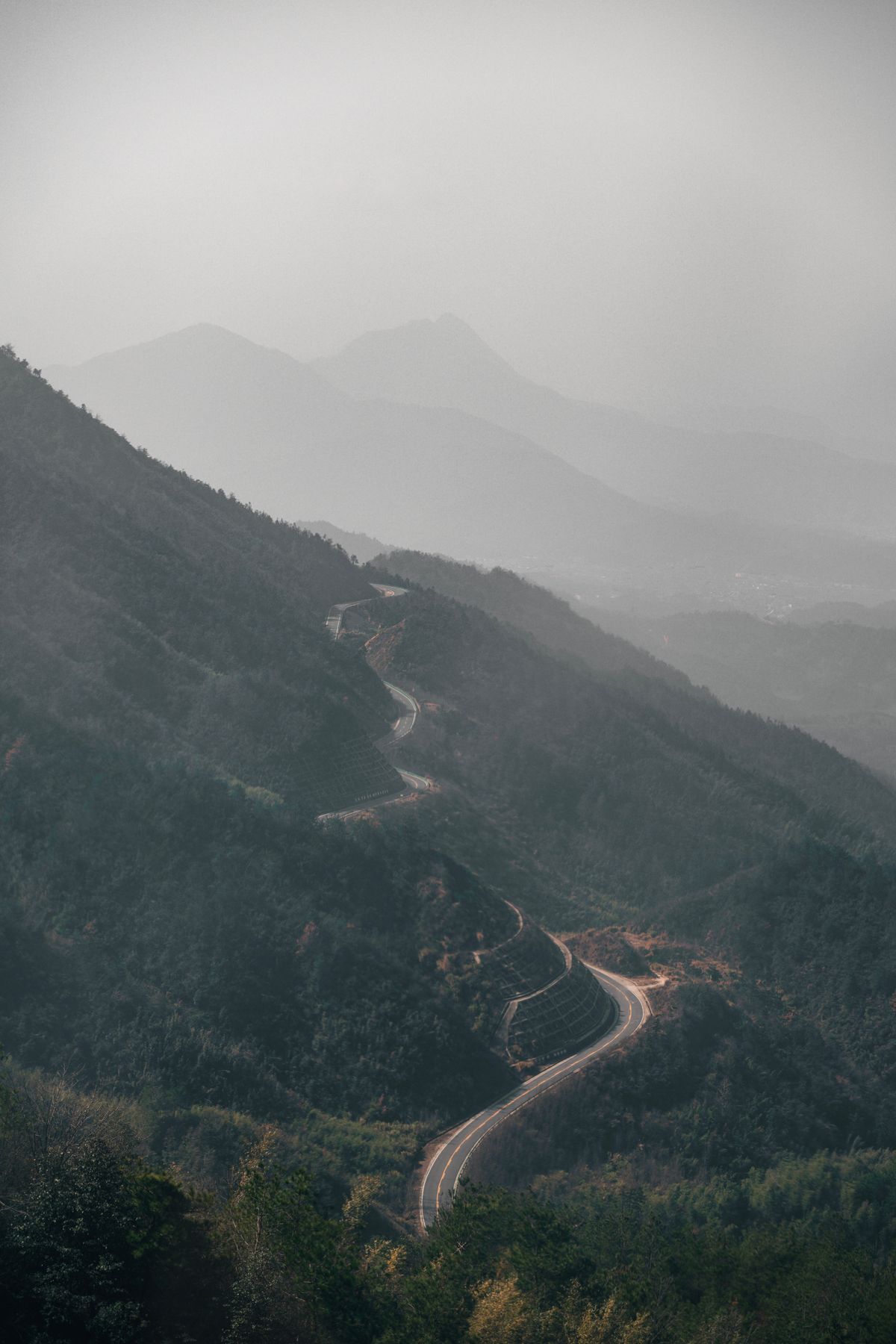 A road winding through misty layered mountains at dawn